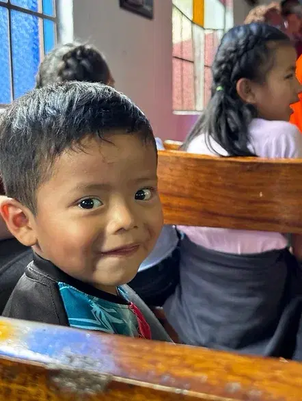 A young boy smiling from the chapel pews at Hogar Miguel Magone