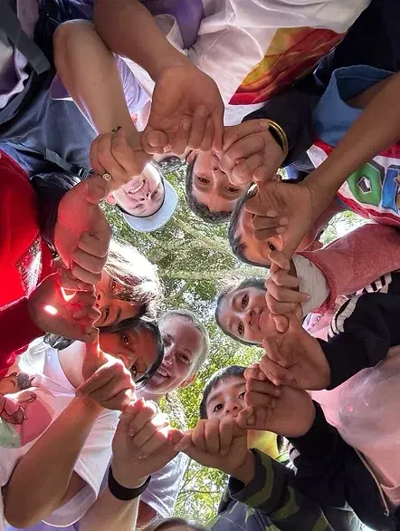 Children and volunteers in a circle, hands together
