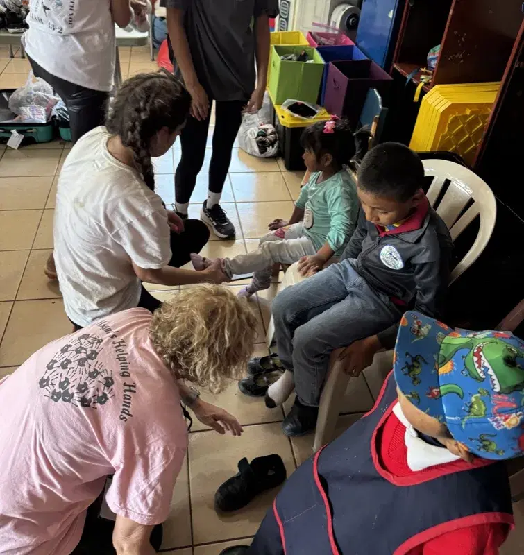 Volunteers fitting children with new shoes