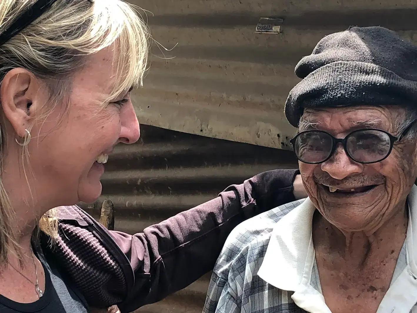 A volunteer sharing a laugh with an elderly man on a home visit in Aguacate