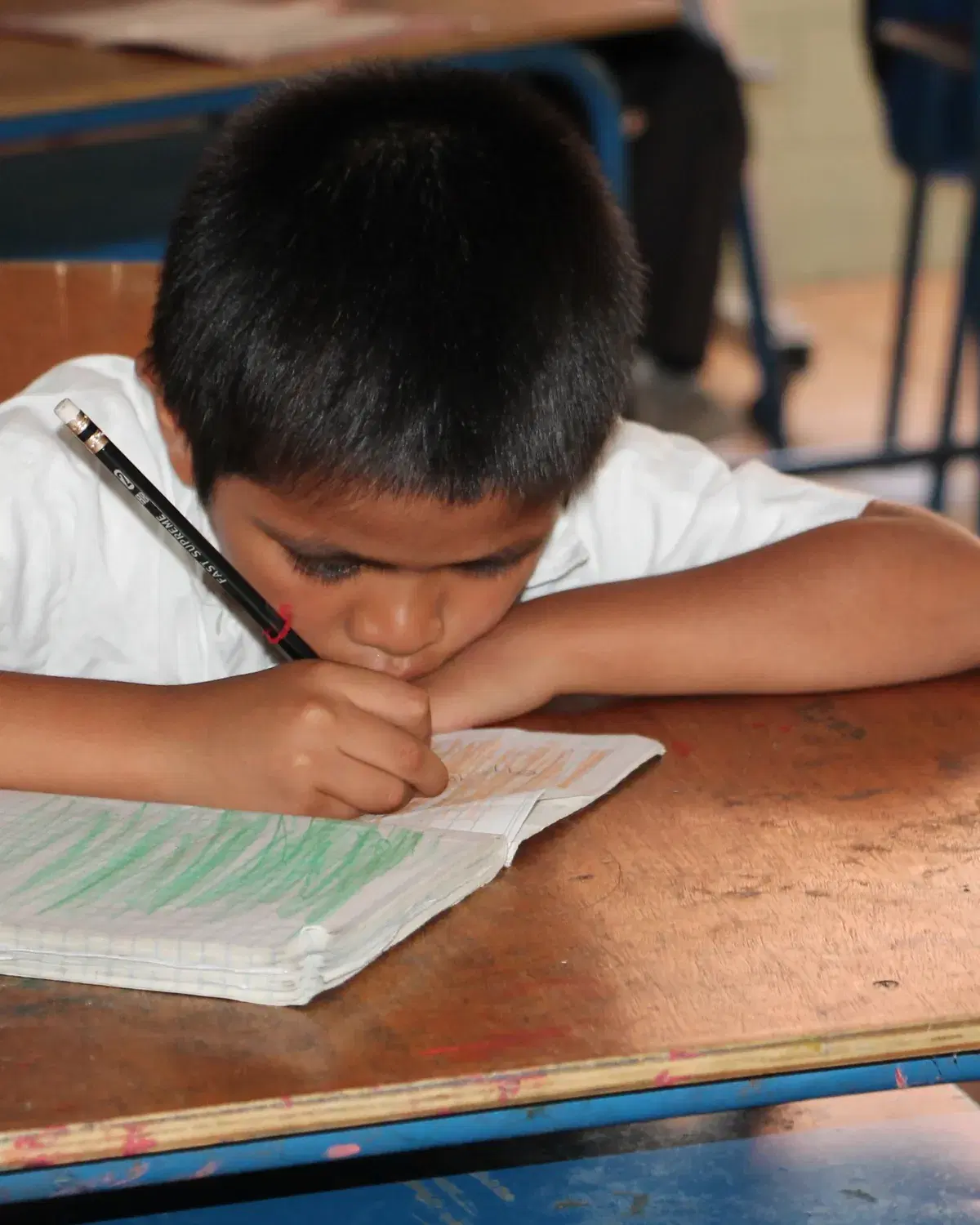 A boy at Hogar Miguel Magone working at his school desk